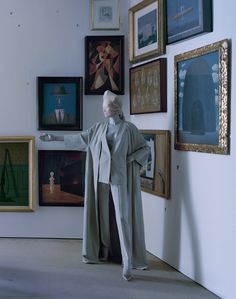 a woman standing in front of paintings and wearing a white hat with her arms outstretched