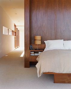 a large bed sitting next to a wooden headboard on top of a white carpeted floor