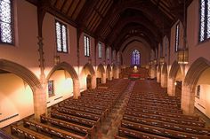 an empty church with rows of pews and stained glass windows on the walls,