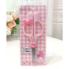 a pair of pink scissors sitting in a box on a table with flowers behind it