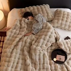 a woman laying on top of a bed under a blanket