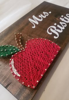 a string art apple sitting on top of a wooden sign