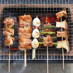 several skewered meats and asparagus on a grill