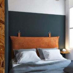 a bed with two pillows on top of it next to a wall mounted light fixture