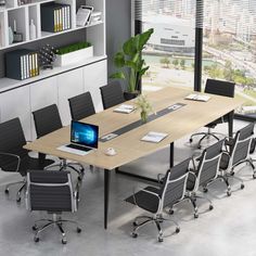 a conference table with black chairs and a laptop on it in front of a large window