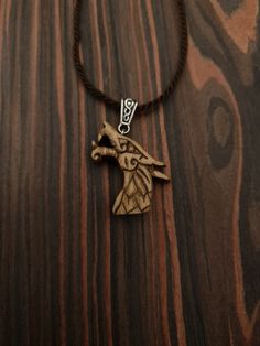 a necklace with a bird on it sitting on top of a wooden table next to a string