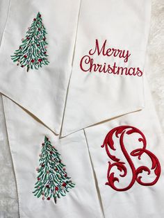 three embroidered christmas napkins with monogramming on them