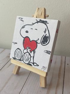 a small easel with a painting of a cartoon character holding a heart on it