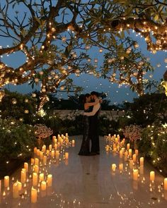 a man and woman standing under a tree covered in candles