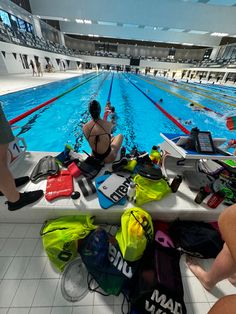 people are sitting on the edge of an indoor swimming pool with equipment all around them