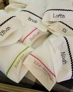 several white napkins with names on them sitting on a table together in a pile