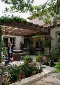 a woman standing in the middle of a patio with potted plants on either side