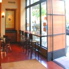 the inside of a restaurant with tables, chairs and large windows looking out onto the street