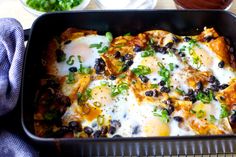 an enchilada casserole with eggs and black beans in a pan