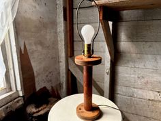 an old fashioned table lamp with a light bulb on it's stand in front of a window