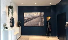 a living room with blue walls and white furniture in the center is an art work on the wall