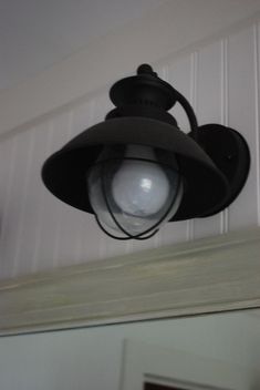 an old fashioned light hanging from the ceiling in a room with white walls and wood paneling