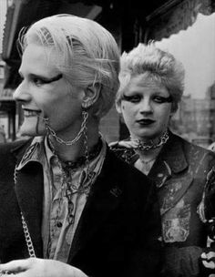 black and white photograph of two women with makeup on their faces, one woman is holding a cell phone