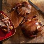 two turkeys sitting on top of a wooden cutting board next to a knife and fork