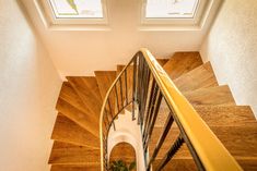 an overhead view of a wooden staircase with two windows on the top and bottom floor