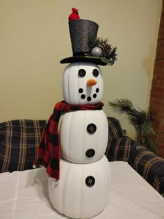 a snowman with a top hat and scarf on it's head sitting on a table