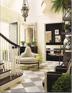 a living room with black and white checkered flooring, chandelier hanging from the ceiling