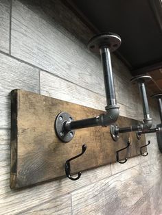 an industrial style coat rack is mounted on the wall with two hooks and one hook