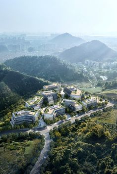 an aerial view of a large building in the middle of trees and mountains with buildings on each side