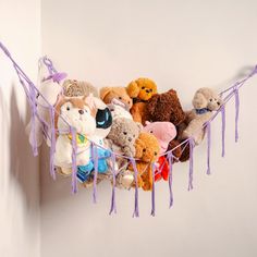 a bunch of stuffed animals are hanging on the wall with tassels around them