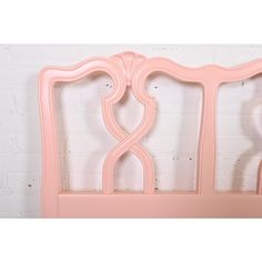 a pink bed frame against a white brick wall with an arched design on the headboard