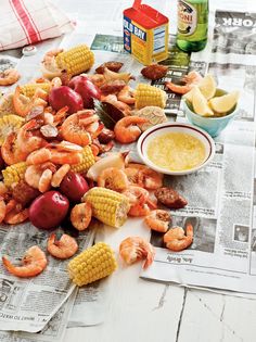 a table topped with lots of food next to corn on the cob