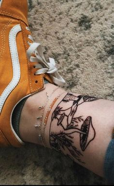 a person's foot with tattoos on it and an orange sneaker in the background