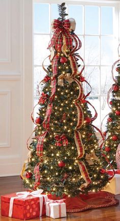 two christmas trees decorated with red and gold ribbons, wrapped in bows are sitting next to each other