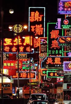 a busy city street filled with lots of neon signs and traffic lights at night time