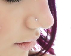 a close up of a woman's nose with piercings on her nose and purple hair