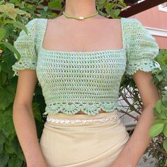 a woman wearing a green crochet top and tan skirt