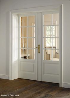 an open white door in a room with wooden floors and windows on either side of the doors