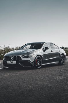 a mercedes cla is parked on the side of the road in front of some bushes