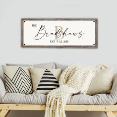 a couch with pillows and blankets on top of it in front of a white wall