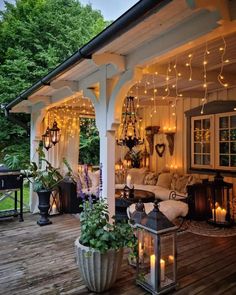 an outdoor living area with lights strung from the ceiling and potted plants on the deck