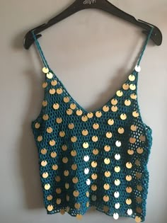 a blue top with gold sequins hanging on a hanger