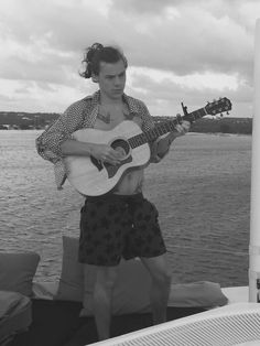 a man holding a guitar on top of a boat