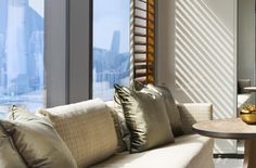 a living room filled with lots of furniture next to a window covered in blinds and pillows