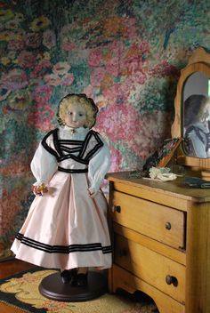 a doll is standing next to a dresser