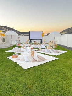 an outdoor movie is set up in the grass with white sheets and pillows on it