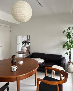 a living room filled with furniture next to a wooden table and black couch in front of a white wall