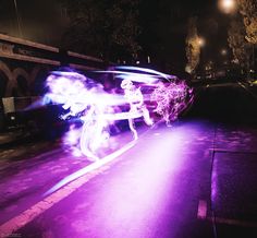 a person riding a bike on a city street at night with purple light in the background