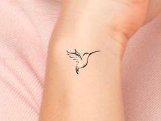 a small black bird tattoo on the left inner arm and wrist is shown in this image