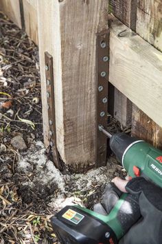 a cordless driller is laying on the ground next to a wooden fence post