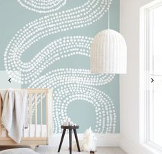 a baby's room with a crib, lamp and wallpaper in shades of blue